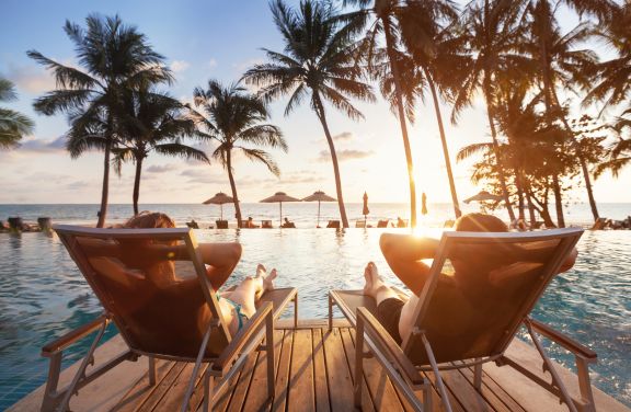 Let Aileen Kucan help you find the ideal setting for your romantic escape, and make every moment count. She has 15 insider secrets for planning the perfect getaway. Couple laying in chairs next to pool.